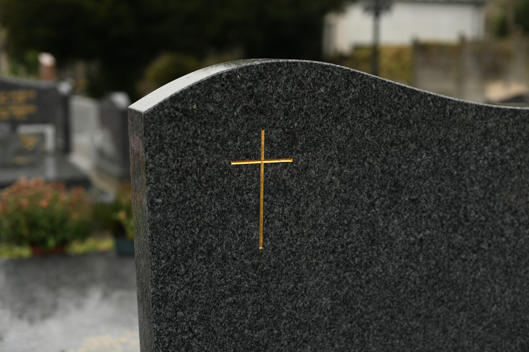 Cross on a black marble slab on a grave in a cemetery
