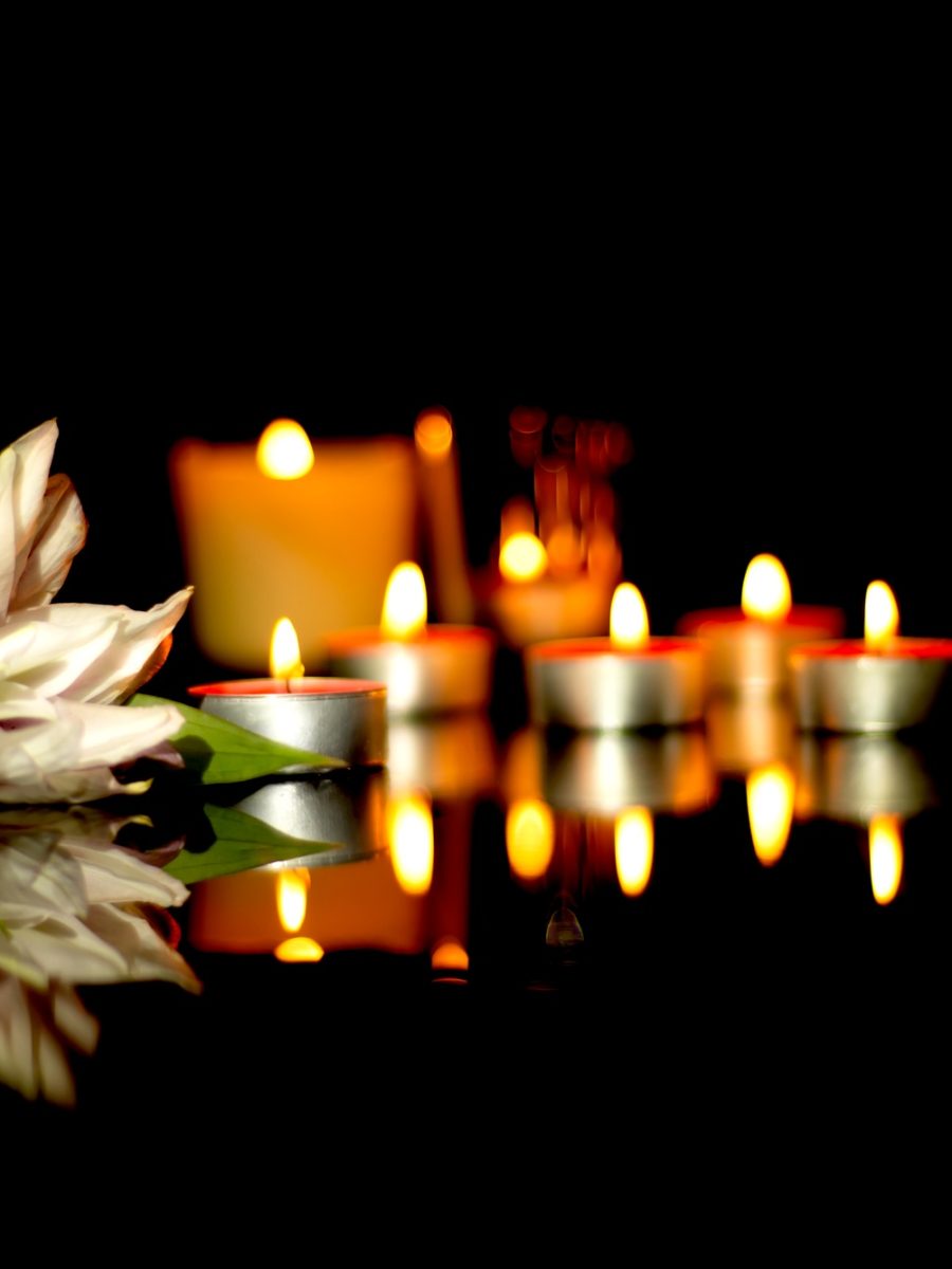 White lily, candles of a funeral on a plaque with the reflection of lights. Mourning background